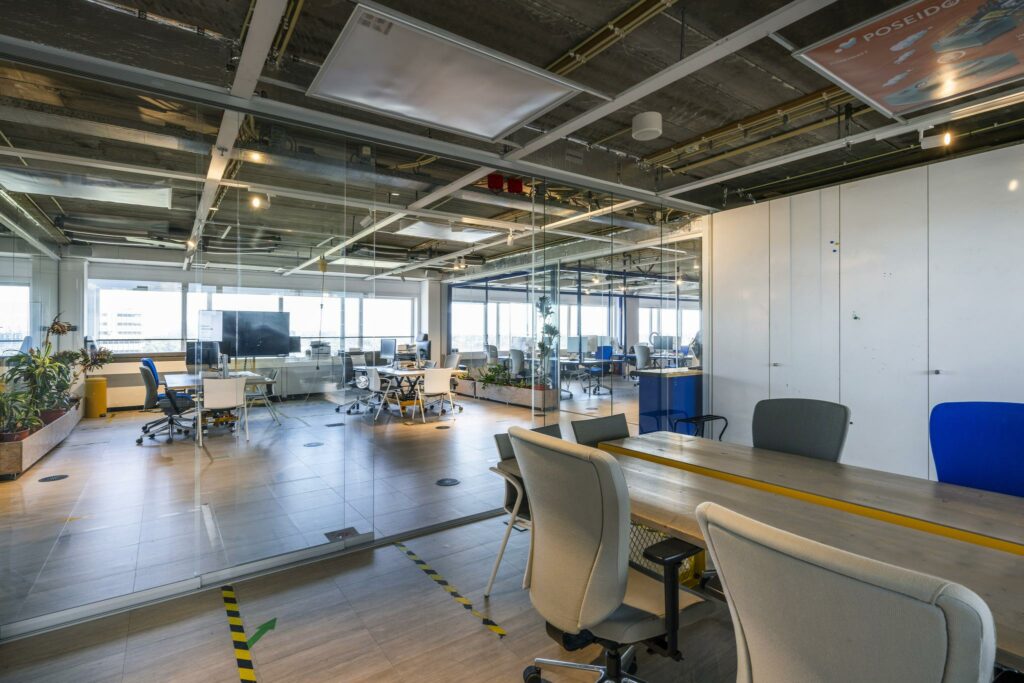 Moderne, open kantoorruimte aan de Johan Huizingalaan met glazen wanden, bureaus en ergonomische stoelen.